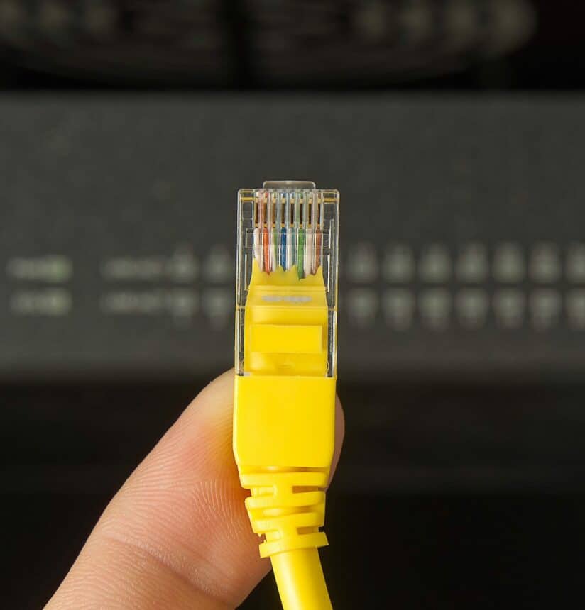 A internet cable that is being pictured in front of the internet switch that is behind the yellow