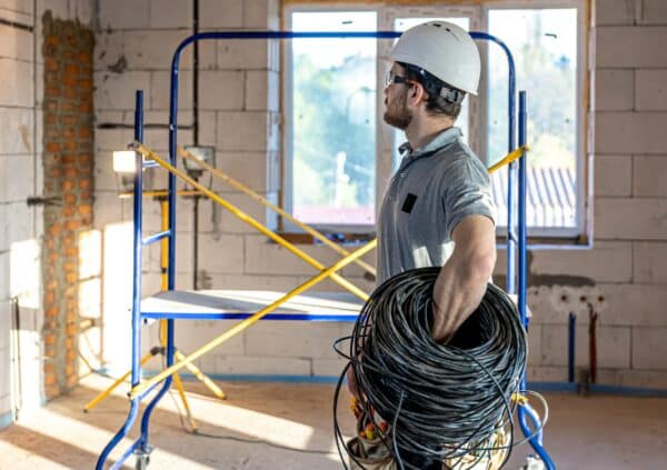 An electrician contractor examines a blueprint at a construction site.