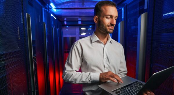 Bearded confident maintenance engineer in white shirt is working in database center