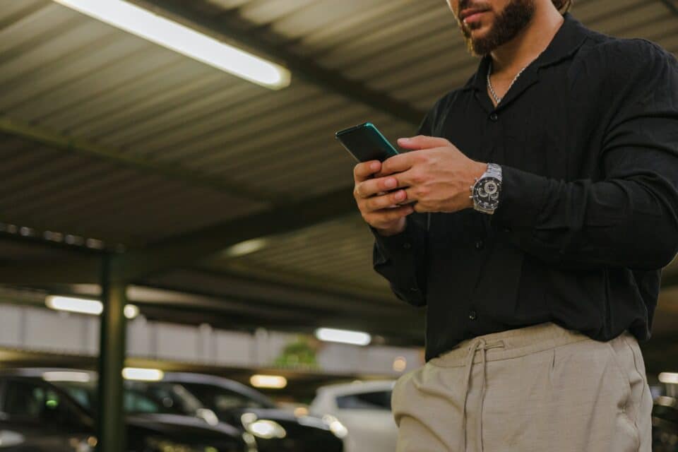Close-up of a businessman with a mobile phone in a parking lot