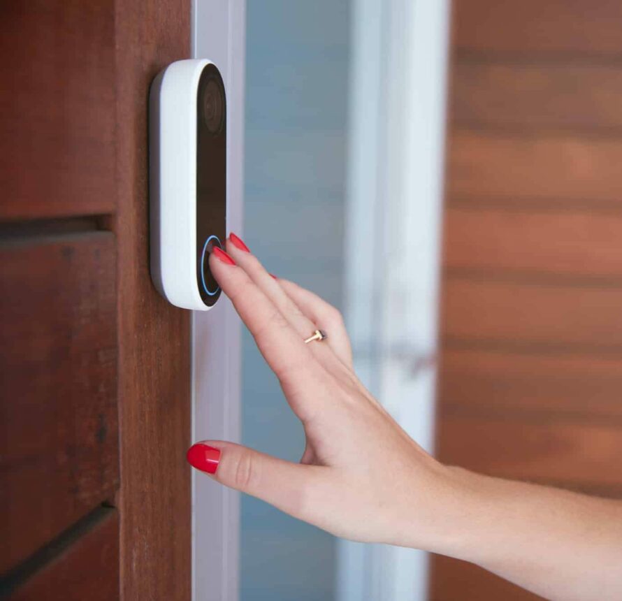 Close Up Of Woman Ringing Front Doorbell Equipped With Security Video Camera