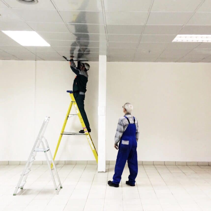 Electricians repair lighting in the trade building