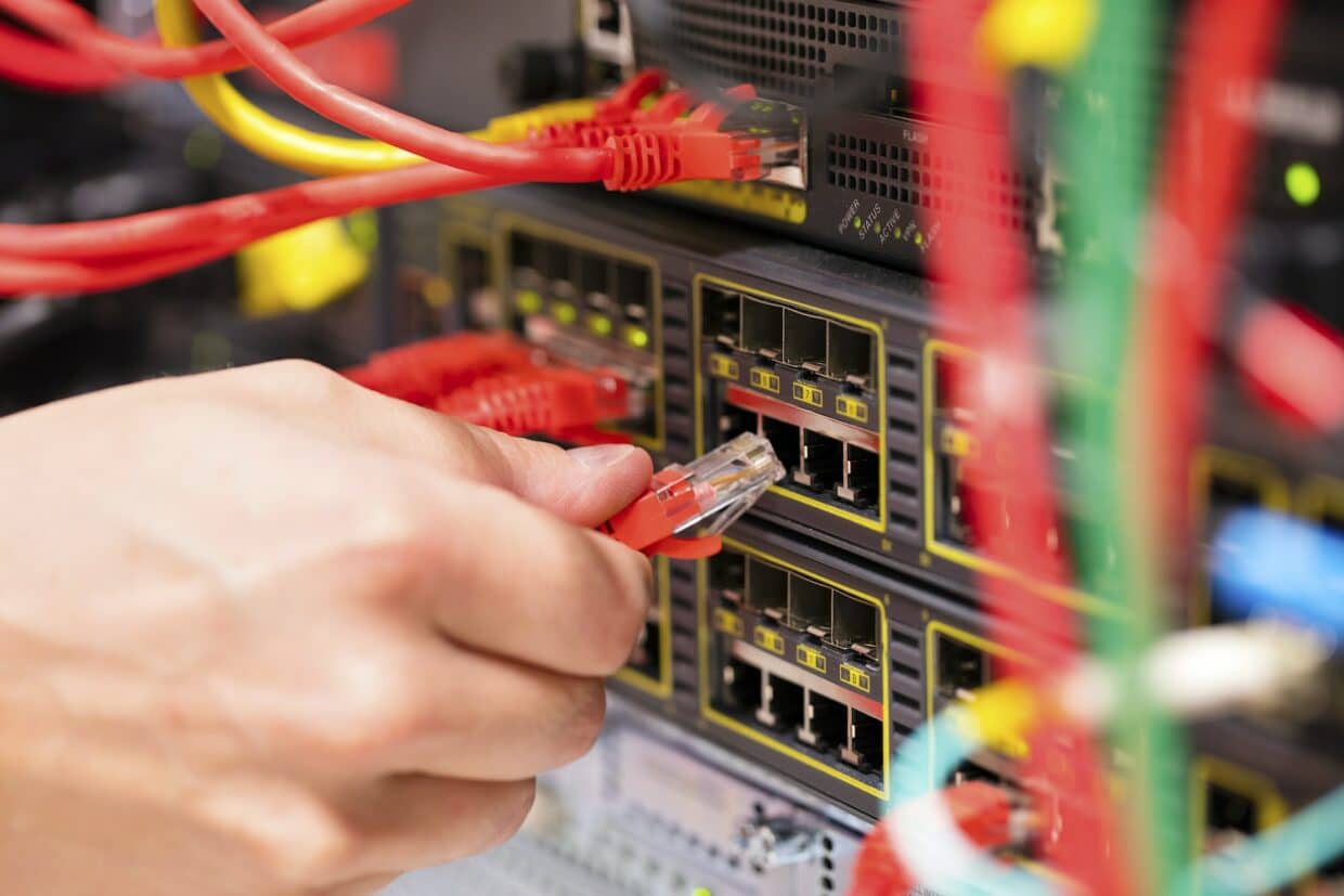 IT consultant connects a network cable into switch in datacenter