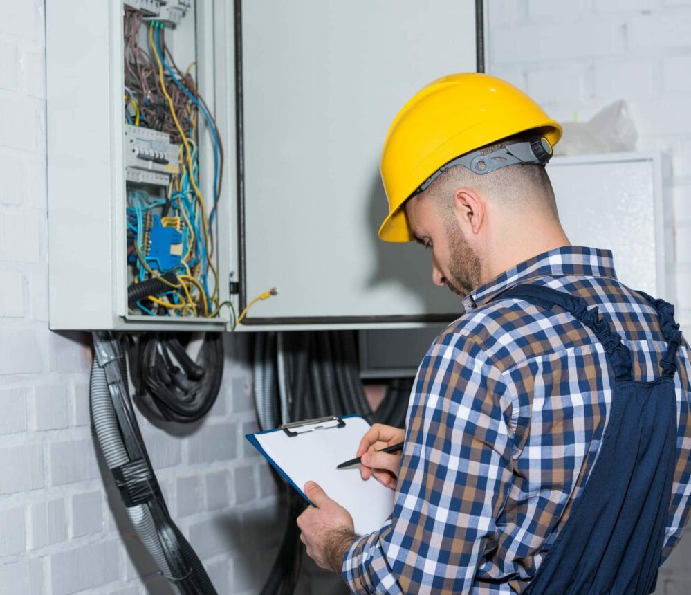 Professional electrician inspecting wires in electrical box