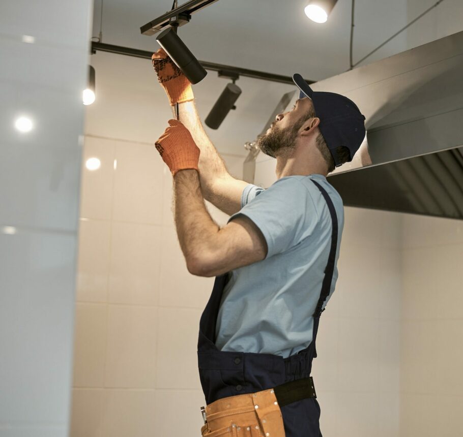 Repairman fixing ceiling lamp in cafe kitchen