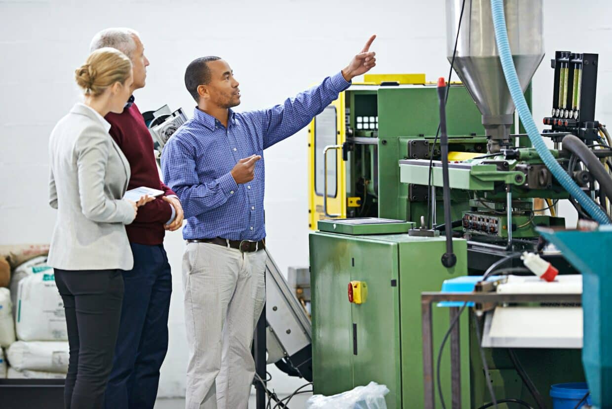 Scheduled maintenance inspection. Shot of a managers inspecting factory machinery.