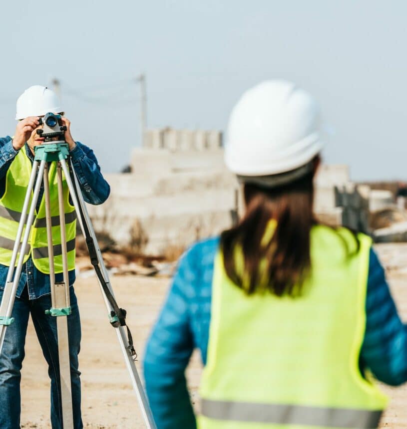 Selective focus of surveyors with digital level and survey ruler on construction site