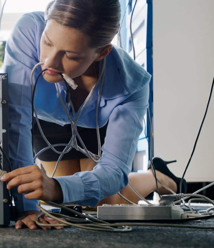 young secretary connecting cables to pc in office