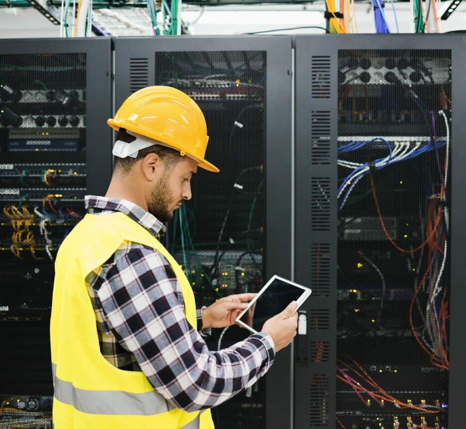 Young technician man working with tablet inside big data center room