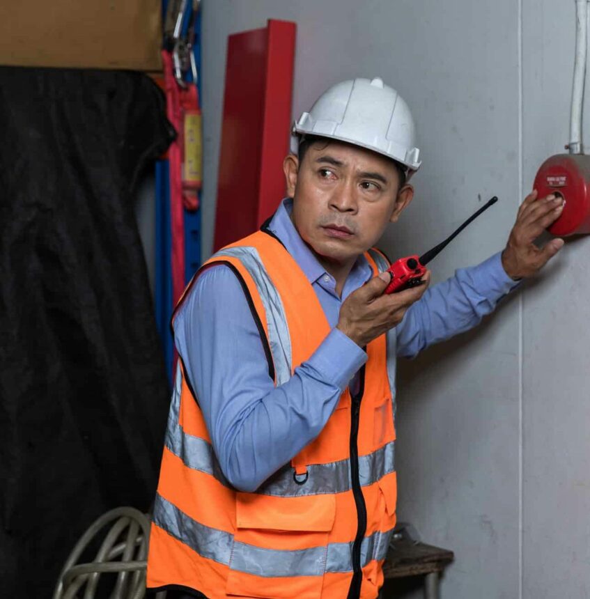 Foreman or worker pushing fire alarm on the wall. A fire! or Emergency case at the factory building.